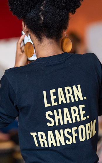 Woman wearing a shirt that says "Learn. Share. Transform."